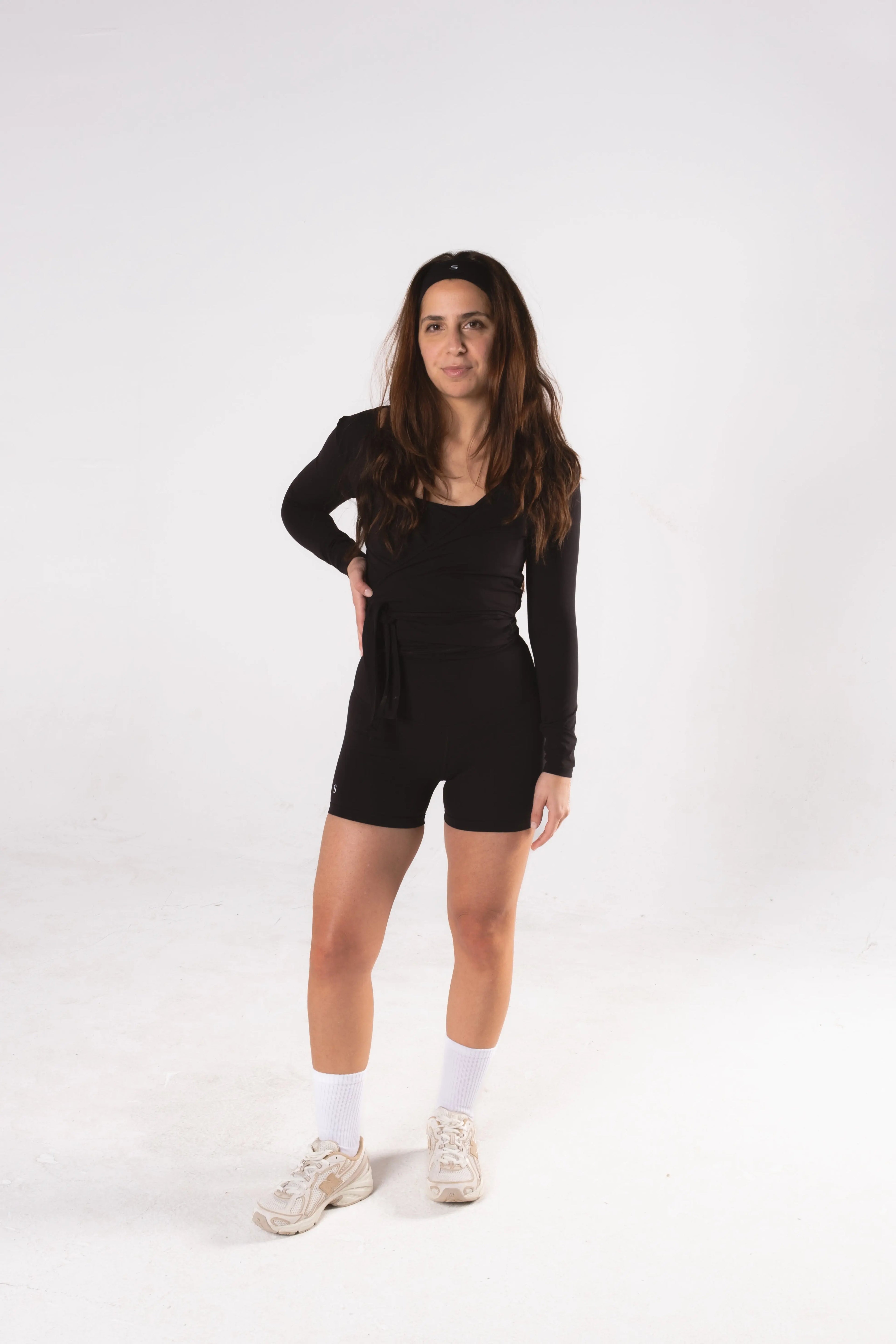Woman wearing LESS Activewear Wrap Top, feminine coverage top for pilates