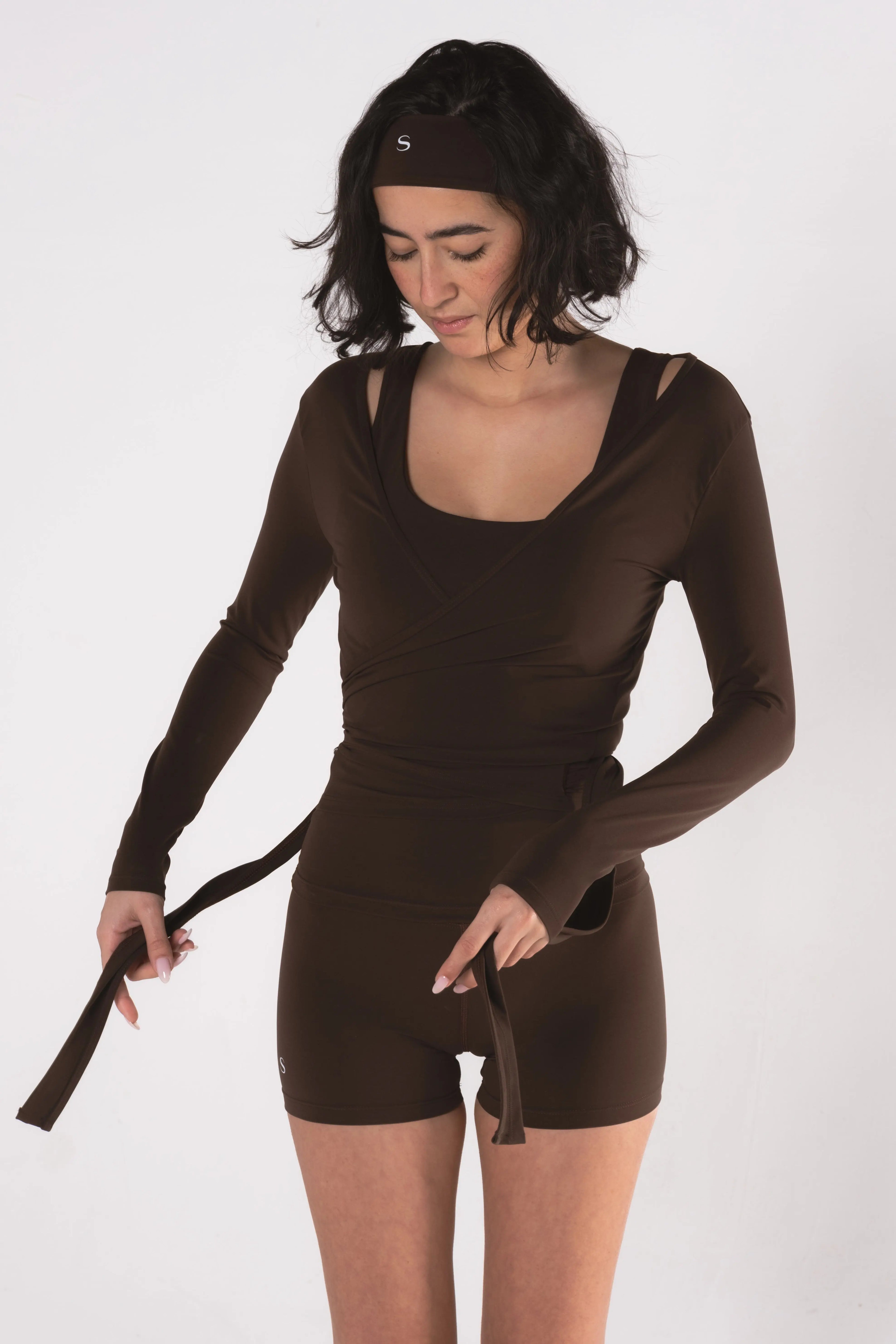 Woman wearing LESS Activewear Wrap Top, feminine coverage top for pilates